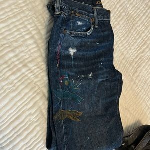Dark blue jeans with floral painting and minimal distress